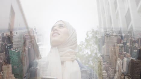 Animation-of-smiling-asian-woman-in-hijab-using-smartphone-over-cityscape