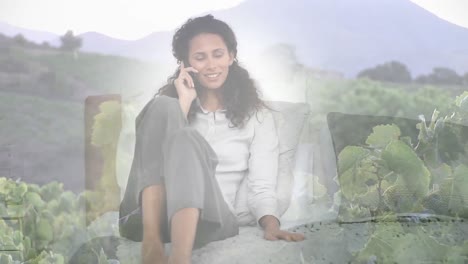 Animation-of-smiling-woman-relaxing-talking-on-smartphone,-over-landscape