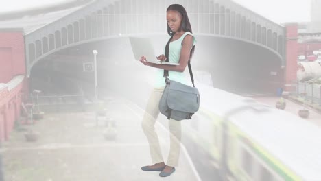 Animation-of-african-american-woman-standing-using-laptop-over-cityscape