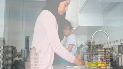 Animation-of-asian-mother-with-daughter-in-kitchen-over-cityscape