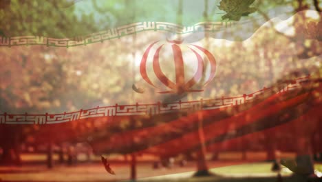 Digitale-Komposition-Der-Iranischen-Flagge,-Die-über-Mehreren-Herbstblättern-Schwenkt,-Die-Gegen-Den-Park-Fallen
