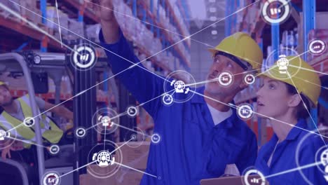 Animation-of-network-of-connections-with-icons-over-man-and-woman-working-in-warehouse