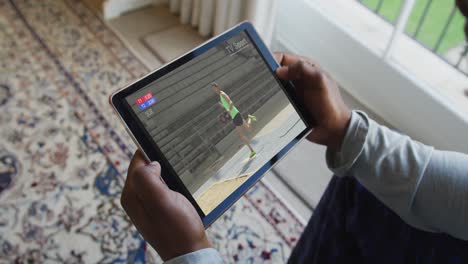 Composite-of-man-sitting-at-home,-watching-athletics-long-jump-event-on-tablet