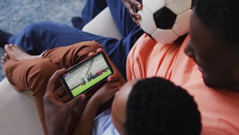 Zusammensetzung-Aus-Vater-Und-Sohn,-Die-Zu-Hause-Ein-Rugbyspiel-Auf-Dem-Smartphone-Ansehen