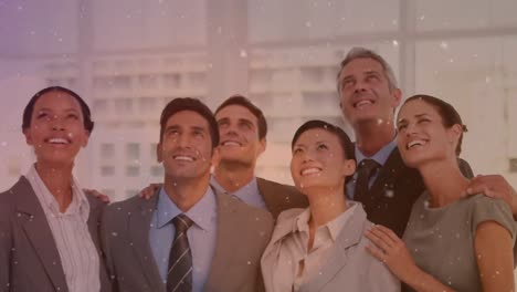 White-particles-floating-against-diverse-businesspeople-looking-up-and-smiling-at-office