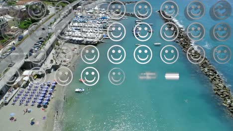 Digital-composition-of-rows-of-multiple-smiling-face-emojis-against-aerial-view-of-the-beach