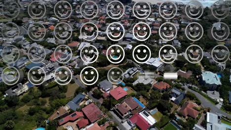 Digital-composition-of-rows-of-multiple-smiling-face-emojis-against-aerial-view-of-cityscape