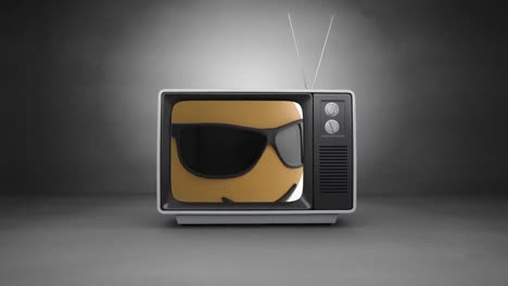 Face-wearing-sunglasses-emoji-on-television-screen-against-grey-background