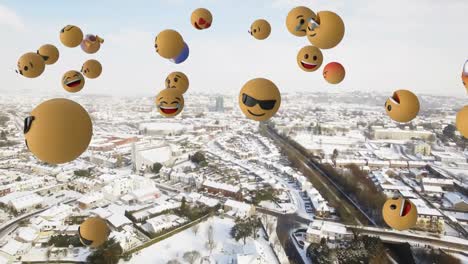 Digital-composition-of-multiple-face-emojis-floating-against-aerial-view-of-snow-covered-cityscape