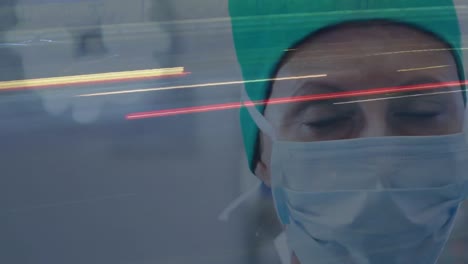Digital-composition-of-portrait-of-female-surgeon-wearing-face-mask-at-hospital-against-city-traffic