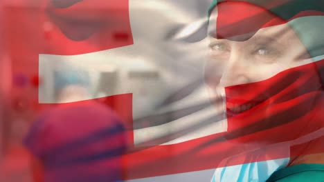 Digital-composition-of-switzerland-flag-waving-over-portrait-of-female-surgeon-smiling-at-hospital