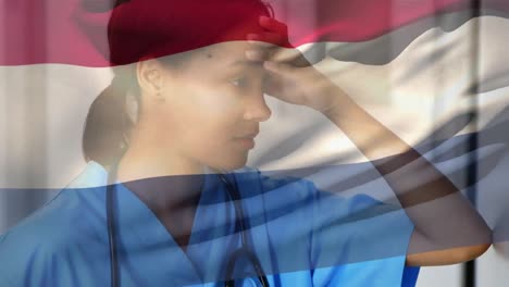 Netherlands-flag-waving-over-stressed-african-american-female-health-worker-at-hospital