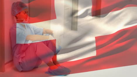 Switzerland-flag-waving-against-stressed-caucasian-female-health-worker-at-hospital