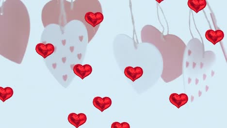 Multiple-red-heart-shaped-balloons-floating-against-hanging-heart-shape-decorations
