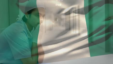 Digitale-Komposition-Einer-Nigerianischen-Flagge,-Die-Im-Krankenhaus-Gegen-Einen-Gestressten-Kaukasischen-Männlichen-Chirurgen-Weht