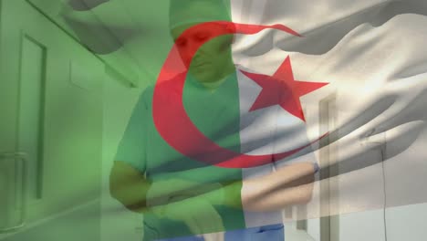Die-Algerische-Flagge-Weht-Gegen-Einen-Kaukasischen-älteren-Männlichen-Gesundheitshelfer,-Der-Im-Krankenhaus-OP-Handschuhe-Trägt