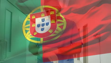 Die-Portugiesische-Flagge-Weht-Gegen-Einen-Kaukasischen-älteren-Männlichen-Gesundheitshelfer,-Der-Im-Krankenhaus-OP-Handschuhe-Trägt