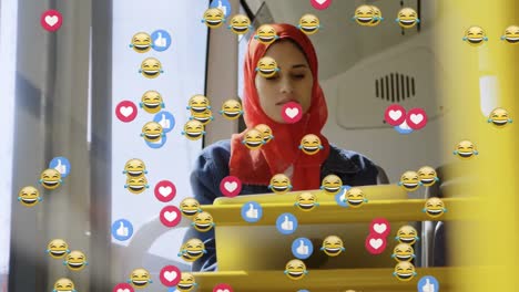 Animation-of-falling-social-media-icons-and-emojis-over-woman-in-hijab