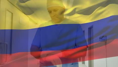 Kolumbien-Flagge-Weht-Gegen-Einen-Kaukasischen-älteren-Männlichen-Gesundheitshelfer,-Der-Im-Krankenhaus-OP-Handschuhe-Trägt