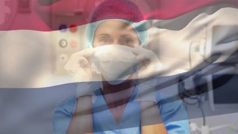 Netherlands-flag-waving-over-female-senior-health-worker-wearing-face-mask-at-hospital