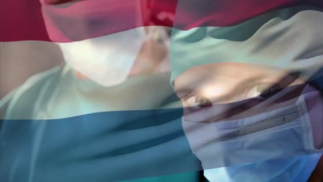 Netherlands-flag-waving-against-female-senior-surgeon-wearing-face-mask-at-hospital