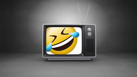 Digital-animation-of-laughing-face-emoji-on-television-screen-against-grey-background