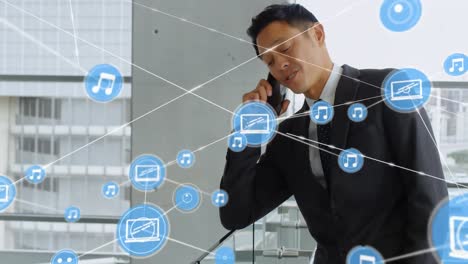 Netzwerk-Digitaler-Symbole-Gegen-Asiatische-Geschäftsleute,-Die-Im-Büro-Auf-Dem-Smartphone-Sprechen