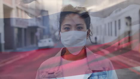 Russland-Schwenkt-Flagge-Gegen-Porträt-Einer-Asiatischen-Frau-Mit-Gesichtsmaske-Auf-Der-Straße