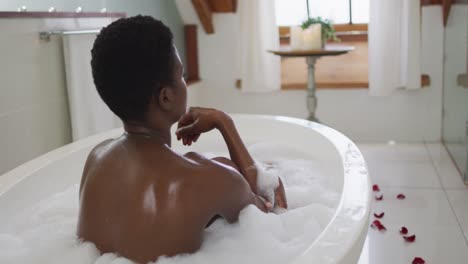 Back-view-of-african-american-attractive-woman-relaxing-in-foam-bath-in-bathroom