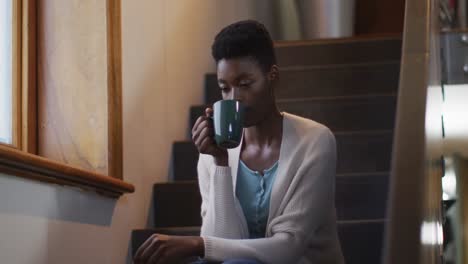 Nachdenkliche-Afroamerikanische-Attraktive-Frau-Sitzt-Auf-Der-Treppe-Und-Trinkt-Kaffee