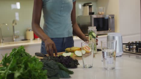 Mittelteil-Einer-Afroamerikanischen-Attraktiven-Frau,-Die-Smoothie-In-Der-Küche-Zubereitet