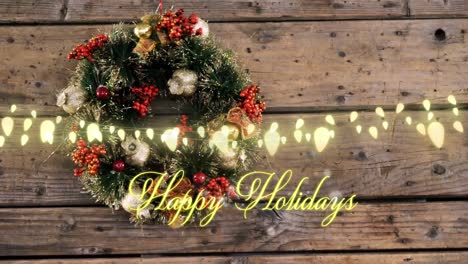 Animation-of-happy-holidays-text-over-wreath-on-wooden-background