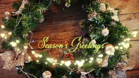 Animation-of-seasons-greetings-text-over-wreath-on-wooden-background