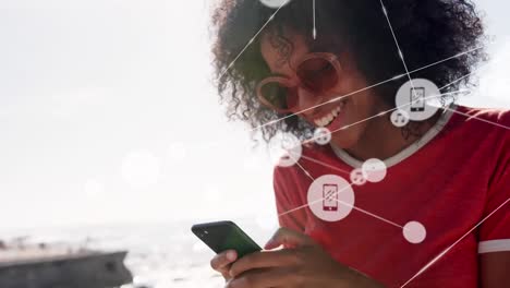 Animation-of-network-of-connections-over-woman-using-phone-on-the-beach