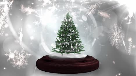 Animation-of-christmas-tree-in-snow-globe,-with-falling-snowflakes-and-glowing-lights-on-grey