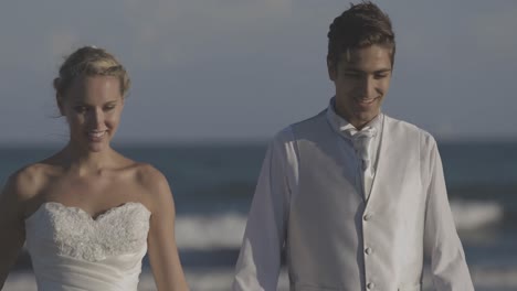 Smiling-newlyweds-running-on-the-beach