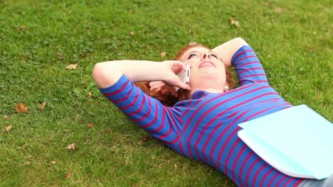 Smiling-student-lying-on-grass-talking-on-the-phone