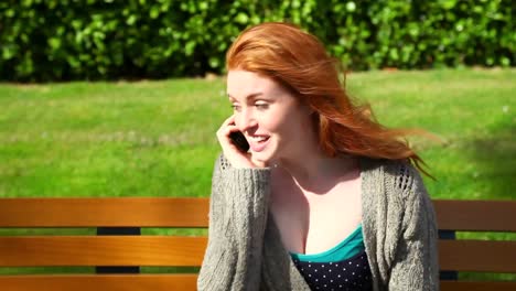 Cute-woman-sitting-on-bench-while-phoning