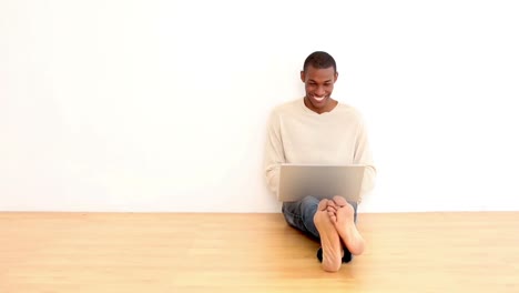 Hombre-Sonriente-Usando-Una-Computadora-Portátil-Sentado-En-El-Suelo