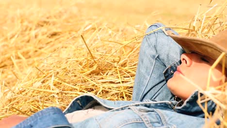 Peaceful-woman-wearing-cowboy-hat-lying-in-hay