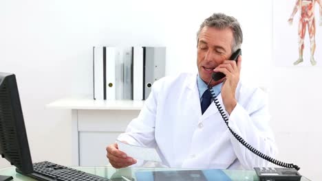Mature-doctor-talking-on-the-phone-at-his-desk