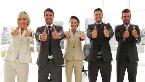 Business-people-giving-thumbs-up-standing-in-a-row