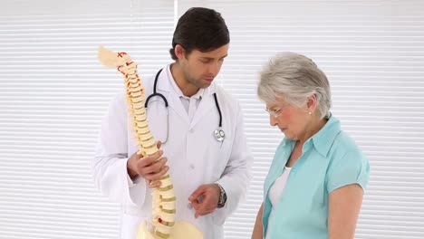 Chiropractor-explaining-spine-model-to-retired-patient