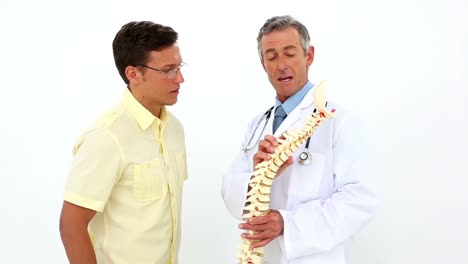 Doctor-holding-model-of-spine-talking-to-patient