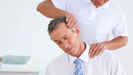 Physiotherapist-giving-businessman-a-neck-massage