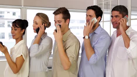 Businesspeople-phoning-while-standing-in-a-row-