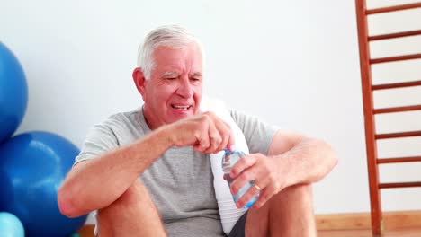 Senior-man-drinking-water-sitting-on-floor