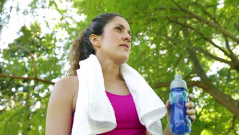 Frau-Wischt-Sich-Nach-Dem-Training-Im-Park-Die-Stirn-Und-Trinkt-Wasser