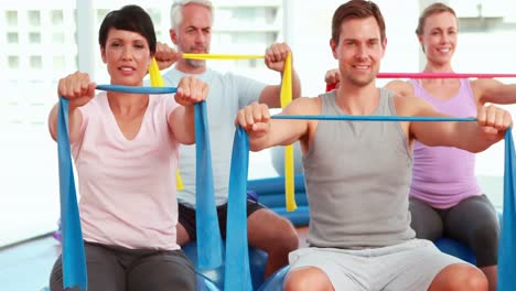 Group-sitting-on-exercise-balls-stretching-resistance-bands
