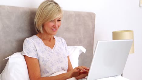 Mujer-Feliz-Usando-Laptop-En-La-Cama